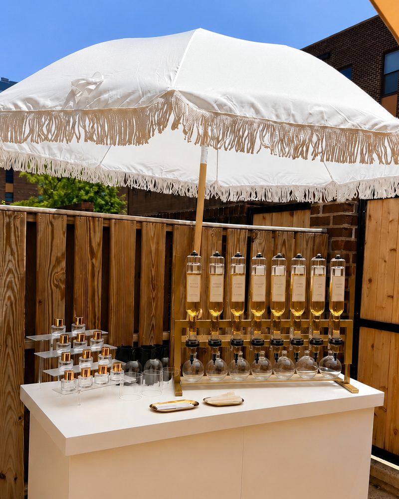 The Philly Scent Club fragrance bar with its gold tincture dispensers and fringed umbrella, set up outdoors